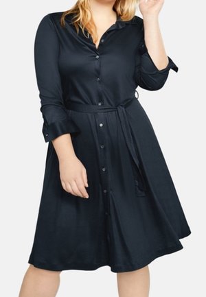 Granatowa sukienka koszulowa na guziki wykonana z gładkiej tkaniny, z długimi rękawami, wiązaniem w talii i rozkloszowanym dołem, tworzącym swobodną sylwetkę.
