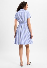 Blue and white striped dress with short sleeves, fitted waist, and flared skirt. Made from a lightweight fabric. Silver sandals featured.