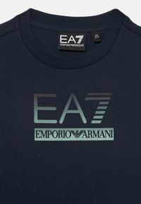 Marineblå bomulls T-skjorte med et stort, reflekterende EA7-logo og teksten "Emporio Armani" i kontrastfarger på forsiden.
