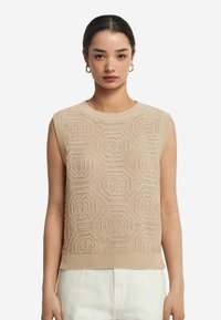 Beige ærmeløs sweater med et struktureret hexagon mønster, ribbet halsudskæring og kant, lavet af et blødt strikkemateriale.