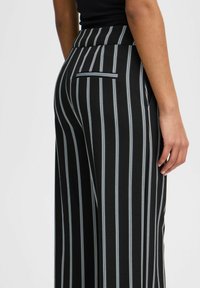 Pantalons rayés noir et blanc avec une taille haute, dotés d'une poche arrière discrète et d'une coupe ajustée élégante.