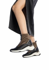 Botines negros y marrones con un diseño elegante, que presentan un zipper en la parte delantera, cuero negro texturizado y una suela blanca con acentos plateados.