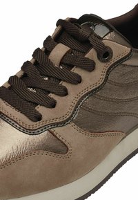 Ruskean mokkanahka sneaker, joka sisältää sekä mattapintaisia että kiiltäviä yksityiskohtia, pyöreät nauhat ja tekstuuripohjan, jossa on hillitty kuvio.