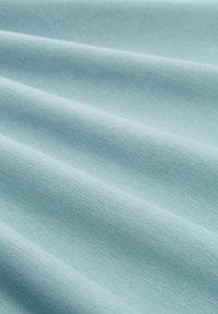 Lichtblauwe katoenen stof met een zachte textuur, die gladde, gelijkmatige plooien en een subtiele glans vertoont, ideaal voor kleding- of bekledingsdoeleinden.