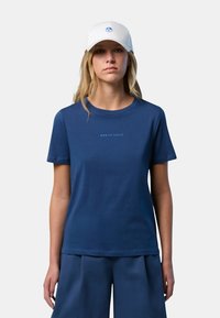 T-shirt in cotone blu navy con scollatura rotonda, maniche corte e testo sottile "NORTH SAILS". Abbinata a pantaloncini blu e un cappellino bianco.
