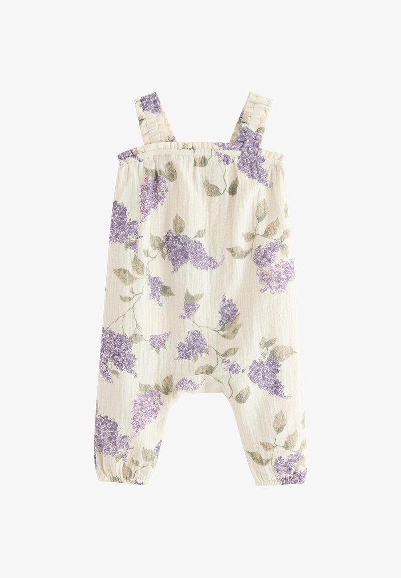 Μπεζ φορμάκι μωρού με μοτίβο μωβ λουλουδιών λιλά, ράντες στους ώμους και ελαστικές ανοίγματα στα πόδια.