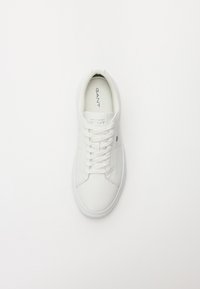 Scarpe da tennis bianche con parte superiore in pelle liscia, punta tonda e lacci piatti. Presentano un branding minimale sulla linguetta e un design semplice.