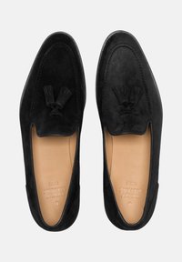 Zwarte suedine loafers met een gladde textuur, kwastaccenten en een lage snit. Het interieur is tan met een reliëfbranding.