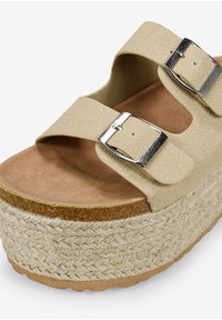 Sandali platform beige con due cinture regolabili, fibbie metalliche e una suola in juta texturizzata. La soletta è imbottita e di colore marrone.