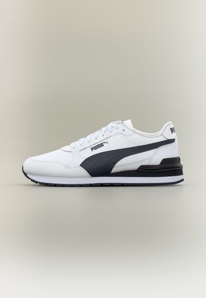 Λευκό και μαύρο αθλητικό παπούτσι Puma με κορδόνια, μαύρη πλευρική ρίγα και λογότυπο Puma στο πλάι και στη φτέρνα, εμφανίζεται σε προφίλ σε ουδέτερο φόντο.