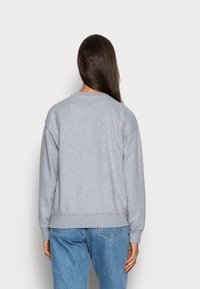 Sudadera gris con cuello redondo, mangas largas, puños y dobladillo acanalados, hecha de una tela suave, con un diseño simple sin patrones.