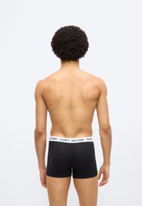 Μαύρα μποξέρ με λευκή ελαστική μέση που φέρει το κείμενο "TOMMY HILFIGER". Απλός σχεδιασμός, εφαρμοστό κομμάτι και απαλή υφή.