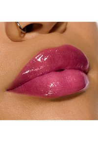 Labbra rosa lucide con effetto sfumato, texture liscia e un leggero luccichio. Il tono della pelle è caldo ed uniforme, mettendo in risalto il colore delle labbra.