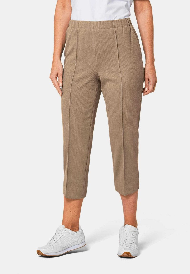 Beige cropped pants met een geribbelde textuur en zijnaaddetails, gecombineerd met witte sportieve schoenen. Elastische tailleband voor comfort.