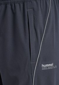Donkergrijze sportshorts van een gestructureerde stof, met een elastische tailleband, zijzak, reflecterende rand en een logo op het onderste deel van het been.