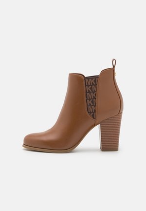 Brauner Leder-Stiefelette mit gestapeltem Blockabsatz und elastischem Seitenpanel mit wiederholtem "MK"-Logo-Muster.
