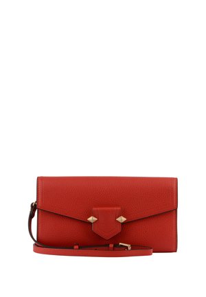 Pochette en cuir rouge texturé avec fermeture à rabat et clous pyramides dorés, accompagnée d'une sangle de poignet amovible.