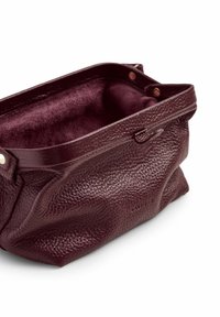 Borsa di cuoio bordeaux con superficie texturizzata, interni morbidi e chiusura a scatto. Design leggermente sfumato con bordi arrotondati e cuciture visibili.