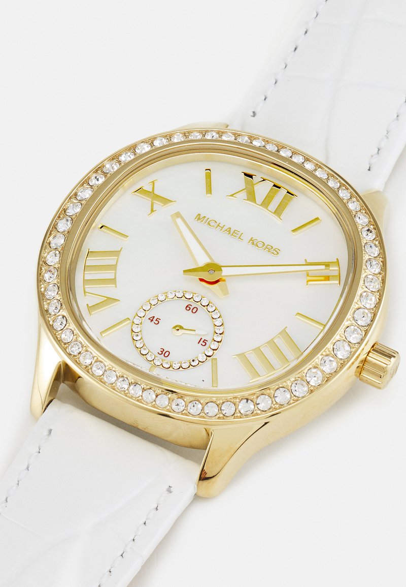 Orologio dorato con cinturino in pelle bianca, quadrante satinato, accenti in cristallo, marcatori in numeri romani e un piccolo quadrante secondario.