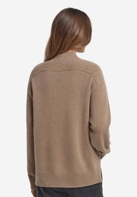 Brązowy sweter z dzianiny z wysokim prążkowanym kołnierzem, opuszczonymi ramionami i prążkowanym dołem. Miękka faktura i luźny krój.