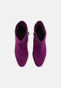Purple suede ankle boots with a tapered toe, zip closure on the side, and a soft interior lining. Smooth texture, mid-height design.