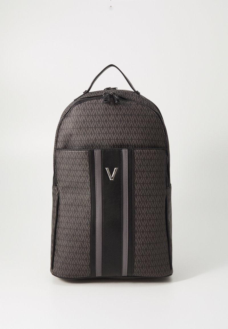 Crni ruksak s uzorkom geometrijskog dizajna, koji ima središnju sjajnu crnu prugu i srebrne metalne dijelove sprijeda.