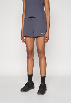 Shorts en mélange de coton bleu marine avec une ceinture élastique et un petit logo blanc. Portés avec des chaussures de sport noires et des chaussettes noires.