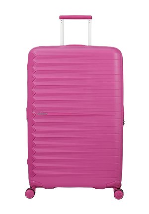 Grande valigia rigida rosa brillante con scanalature orizzontali, manico estensibile e quattro ruote girevoli, in piedi su uno sfondo bianco.