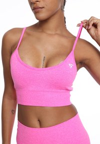 Różowy prążkowany crop top z cienkimi ramiączkami, z wycięciem w kształcie łódki i małym logo z boku. Miękka tekstura i dopasowany krój.