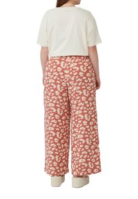 Crème kleur T-shirt, losse pasvorm, gecombineerd met roze broeken met een licht tan luipaardprint. Glad materiaal, wijde broekspijpen, casual stijl.