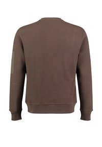 Brązowy, teksturowany sweatshirt z okrągłym dekoltem i długimi rękawami. Posiada jednolity zielony patch na górnej lewej rękawie oraz ściągacze na rękawach.