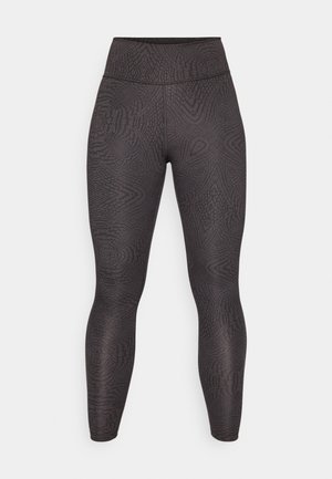 Črne legice z teksturiranim vzorcem zvitkov in črt, visokim pasom in oprijetim krojem, ki sega do gležnjev.