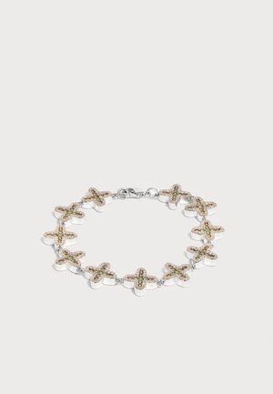 Bracelet en argent avec des breloques en forme de croix liées, décorées de petites pierres scintillantes sur un fond uni.