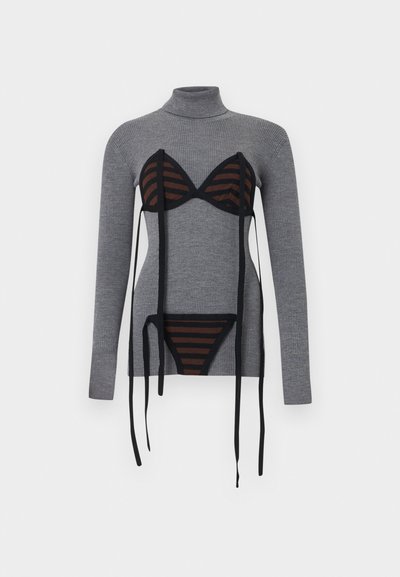 Pull gris à col roulé côtelé avec un ensemble soutiens-gorge et culotte noirs et bruns rayés superposés, doté de longs liens noirs pendants.