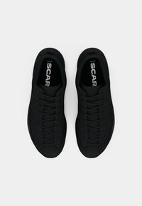 Black athletic shoes with a smooth, textured upper, lace-up design, padded collar, and prominent "SCAR" logo on the insoles.
