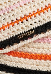 Gehaakt stof met strepen in crème, zwart, oranje en roze; beschikt over een gouden 'SUPERDRY'-label dat opgenaaid is. Textuurpatroon overal aanwezig.