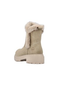 Bottines beige en daim avec un col en fausse fourrure et une semelle chunky beige avec des crampons pour l'adhérence. Logo embossé sur le côté.