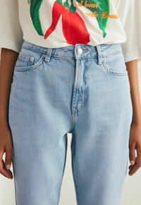Jeans din denim de un albastru deschis, cu talie înaltă, dotate cu buzunare frontale și închidere cu buton. Textură netedă, cu detalii minime de uzură.