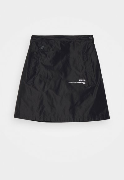 Sort nederdel lavet af glat, letvægtsstof. Har to forlommer, to knapper ved taljen og et mærkelogo trykt i hvidt.