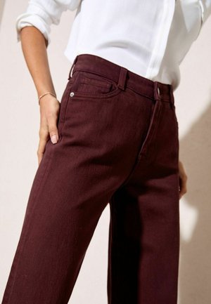 Bordo džinsai su tiesiu kirpimu, pagaminti iš džinsinio audinio. Yra klasikinis penkių kišenių dizainas ir sidabriniai apdailos elementai.