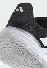 Black knit athletic shoe with a textured upper, white rubber sole, and a reflective iridescent accent along the heel.