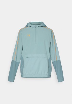 Lichtblauwe pullover jack met een half-rits aan de voorkant, een capuchon, oranje accenten langs de mouwen en een ritszak aan de voorkant. Zachte textuur, atletisch ontwerp.