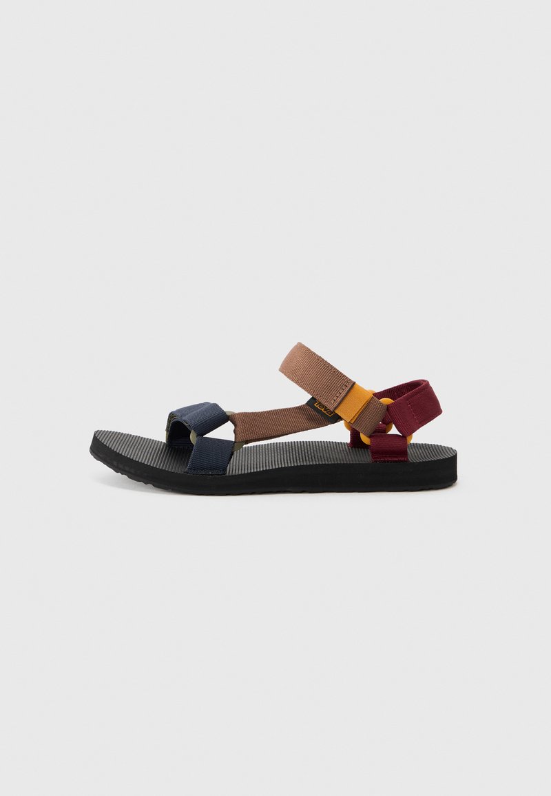 Sandal multicolor con diseño de correas. Presenta correas en tonos azul marino, marrón y burdeos sobre una suela negra texturizada. Ligera y de punta abierta.