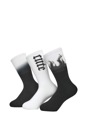 Tre paia di calze alla caviglia: nere con un colore solido, bianche con testo grafico nero e grigio sfumato da nero con design a fiamma sul bordo.