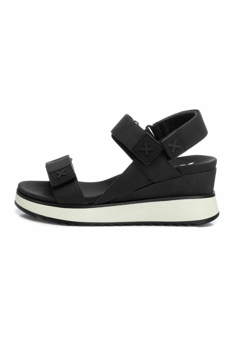 Las sandalias de cuña negras cuentan con dos correas ajustables, una parte superior sintética suave y una entresuela blanca en contraste con una suela texturizada.