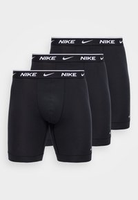 Τρία ζεύγη μαύρα ανδρικά εσώρουχα Nike boxer με λευκό λογότυπο και σήμα swoosh στη λαστιχένια μέση, τοποθετημένα δίπλα-δίπλα σε λευκό φόντο.