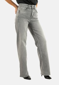 Jeans en denim gris avec une taille haute, coupe droite, poches latérales et décoloration subtile. Présente des coutures robustes et des ourlets nets.
