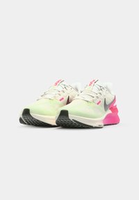 Baskets de sport légères en blanc discret avec des accents verts pastel et roses, tige en mesh et semelle en caoutchouc texturé ; présente des détails réfléchissants.