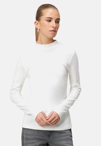 White long-sleeve top with a mock neck, made of smooth fabric. Fitted design with no visible patterns or hardware details.