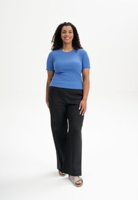 Short-sleeve ribbed blue top paired with black wide-leg trousers, featuring flat sandals with a slight heel and a bow accent.